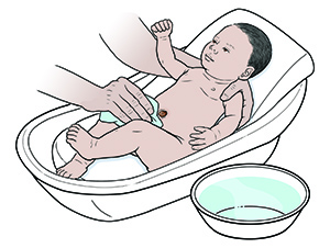 Mano con un paño lava a un bebé recién nacido en la bañera con un recipiente de agua cerca.